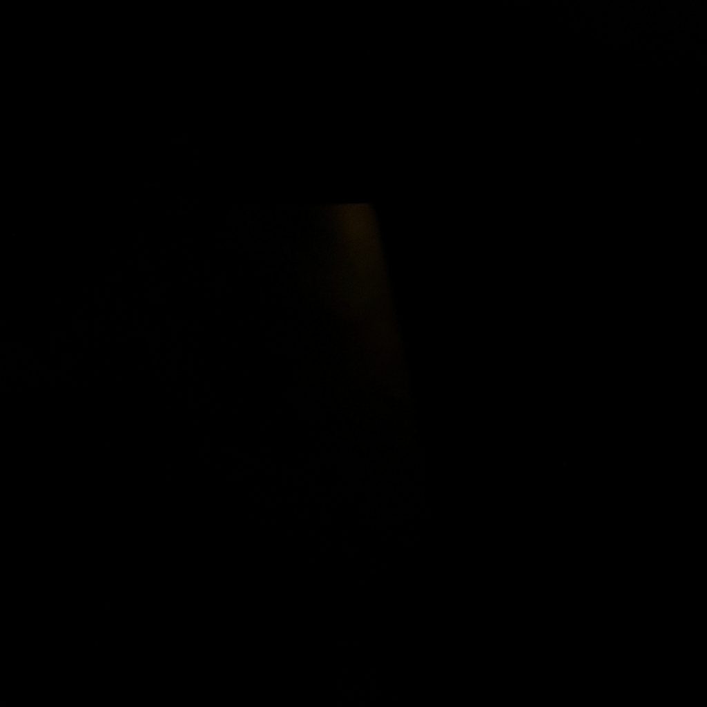 Dark, low-key photograph of an analyst’s desk with a glowing screen, deep navy shadows and a small pool of warm light.